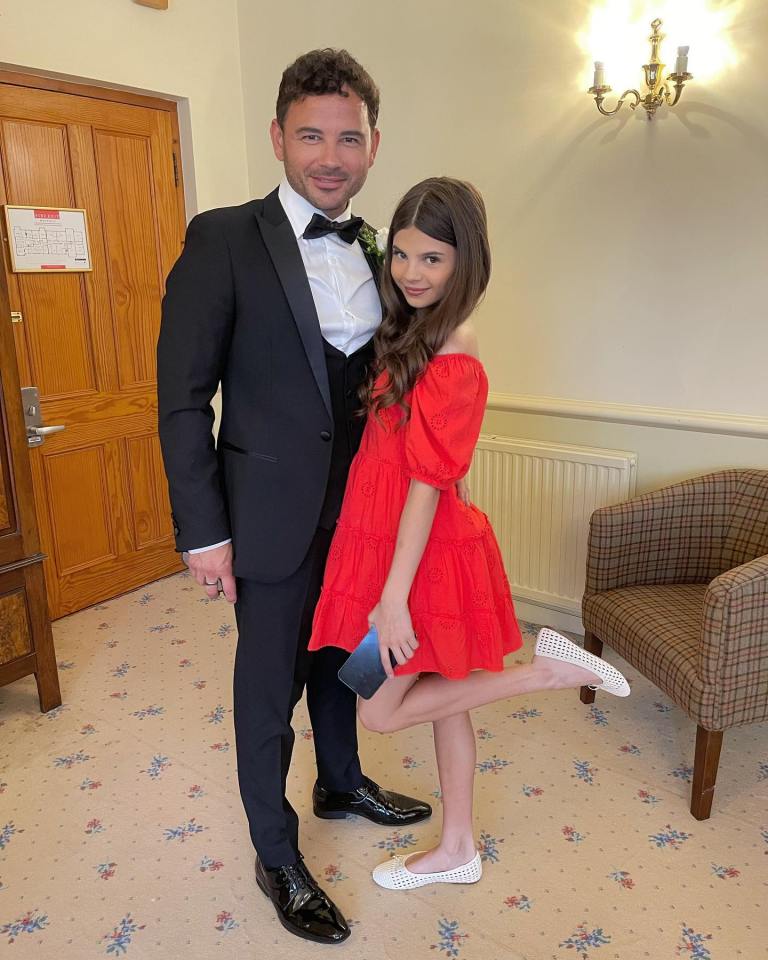 a man in a tuxedo stands next to a girl in a red dress