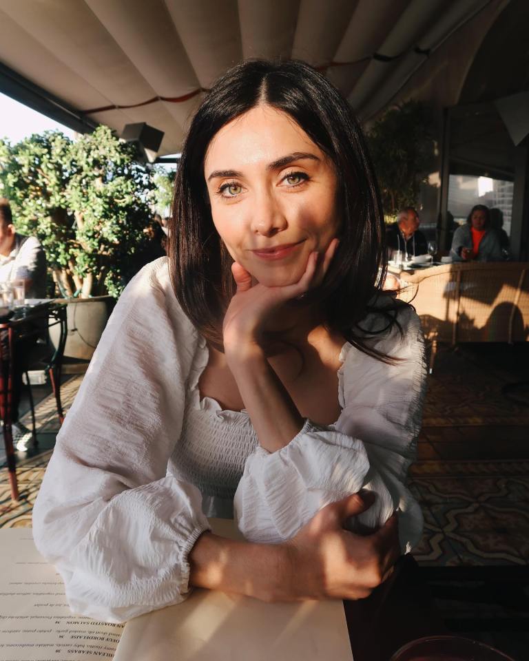 a woman sitting at a table with her hand on her chin