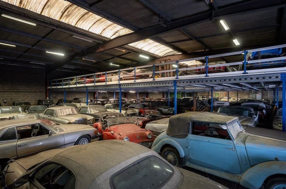 a warehouse filled with old cars including a blue one