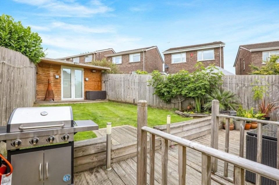 a stainless steel grill is sitting on a wooden deck in a backyard
