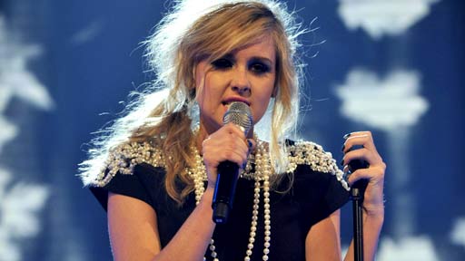 a woman is singing into a microphone on a stage .