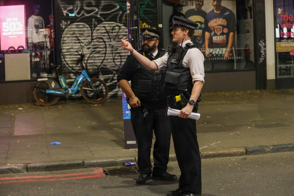 two police officers are standing on a sidewalk in front of a store that has a sign that says 50 % off