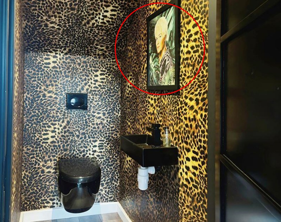 a bathroom with leopard print wallpaper and a black toilet