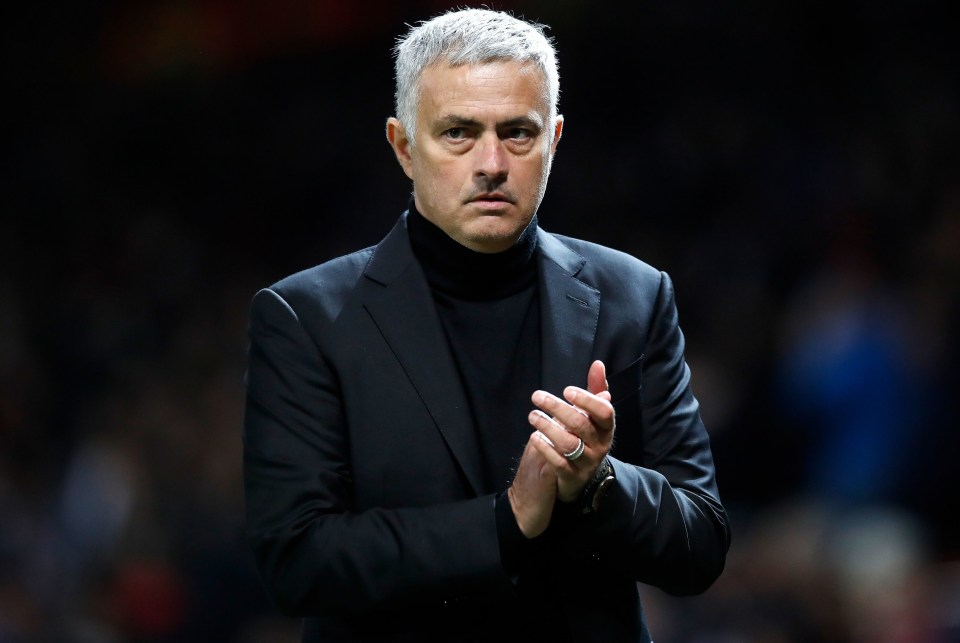 a man in a suit and turtleneck is clapping his hands