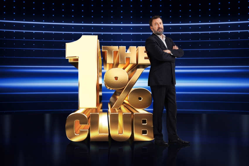 a man stands in front of the 1 % club logo