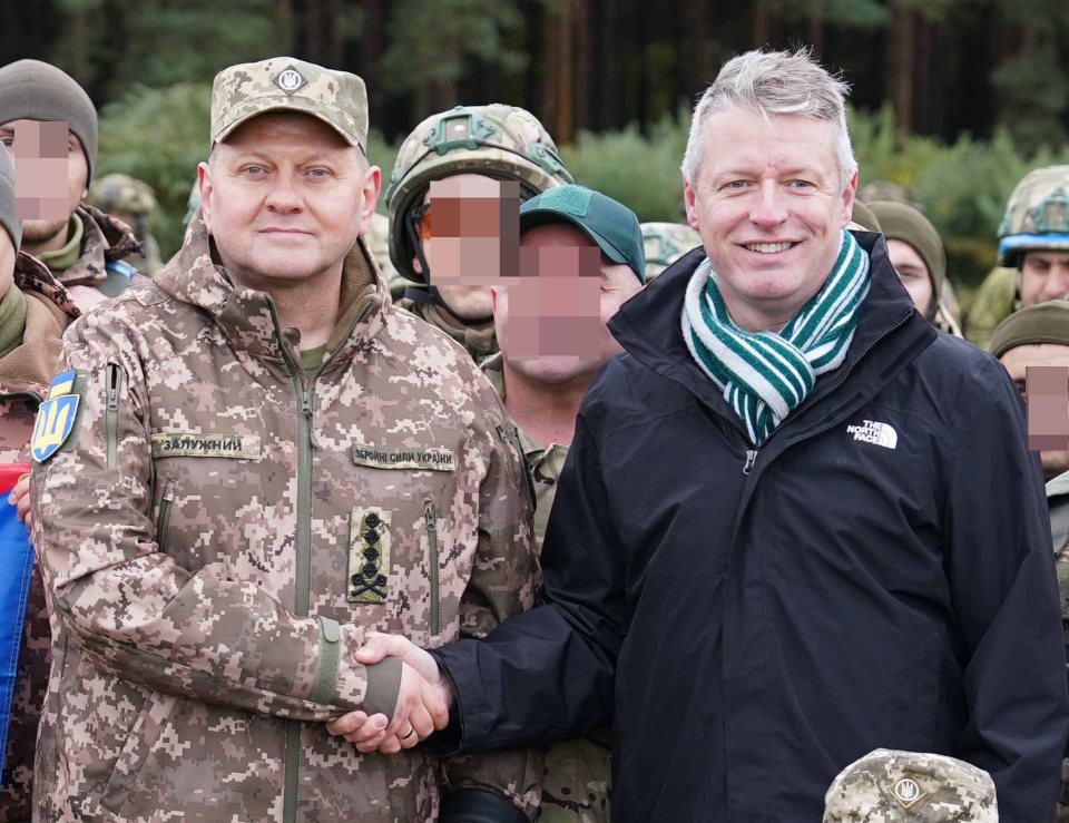 a man in a north face jacket shakes hands with a soldier