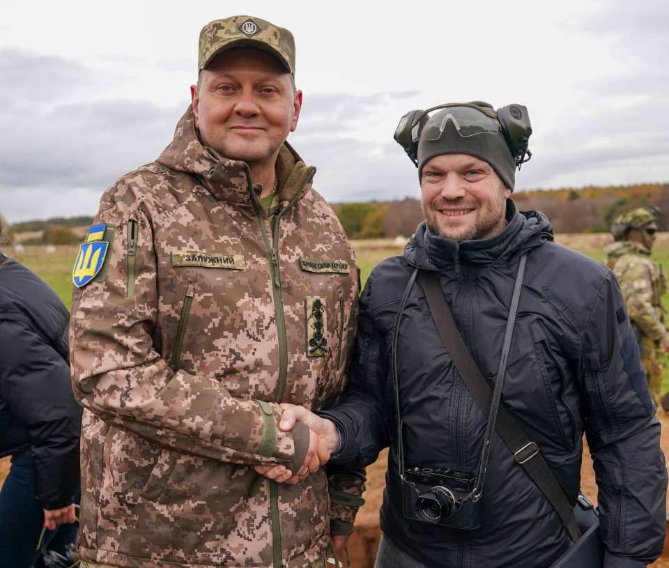 two men in military uniforms shaking hands one of whom has a patch on his jacket that says " 3knpupuh "