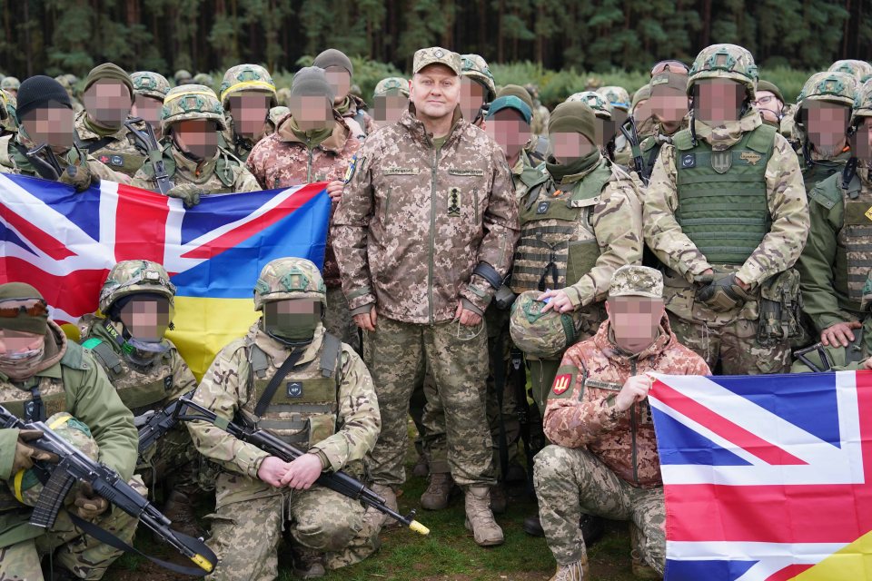 a group of soldiers are posing for a picture and one of the soldiers is wearing a jacket with the letter a on it