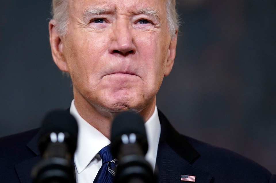 a man in a suit and tie stands in front of two microphones