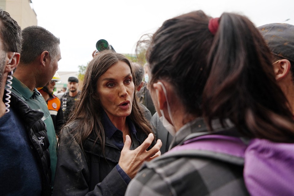 a woman in a black jacket is talking to a group of people