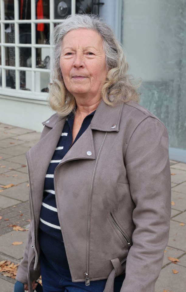 a woman wearing a grey jacket and a blue and white striped shirt