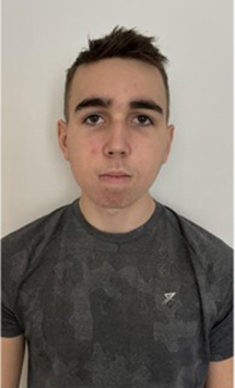 a young man wearing a grey t-shirt with the letter s on it