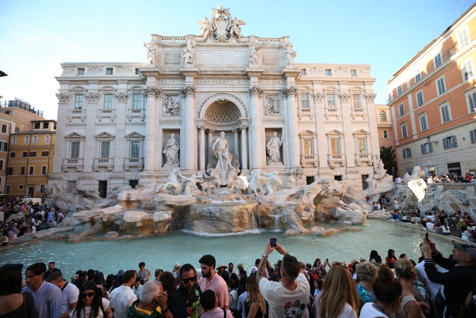 a man taking a picture of a fountain in front of a building
