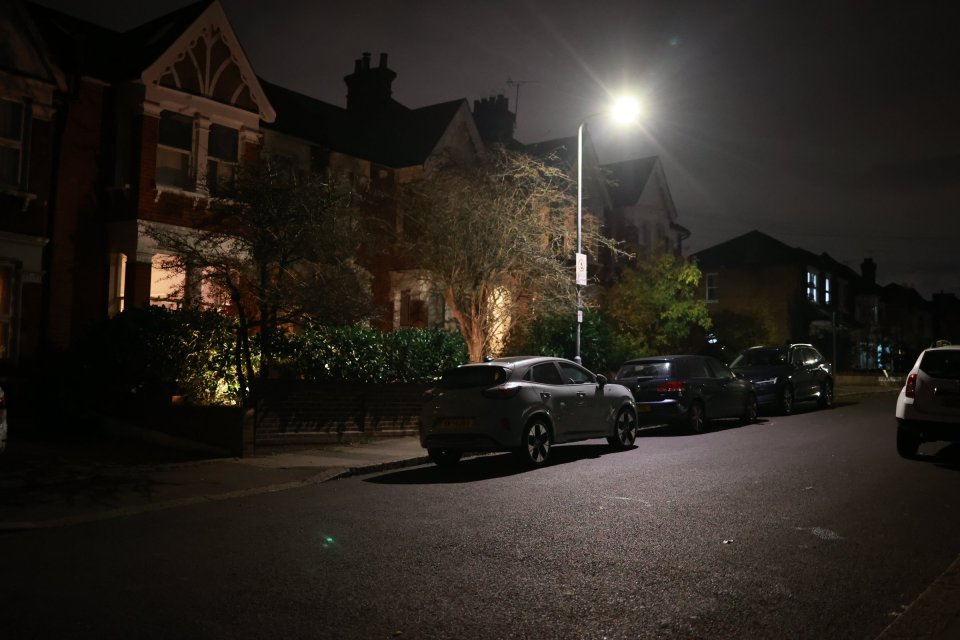 a row of cars are parked on a dark street at night