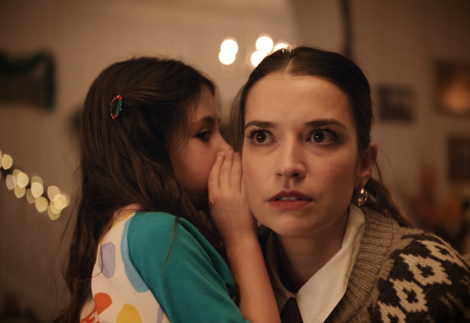 a little girl whispers something into a woman 's ear