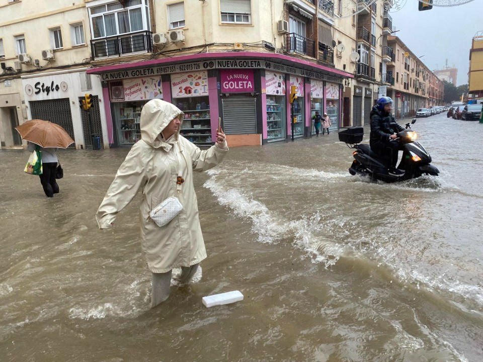 a woman walks through a flooded street in front of a store called la nueva goleta