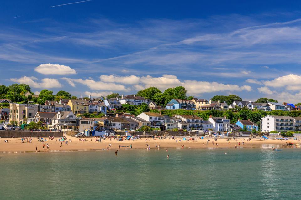 a row of houses sit on a hill overlooking a beach