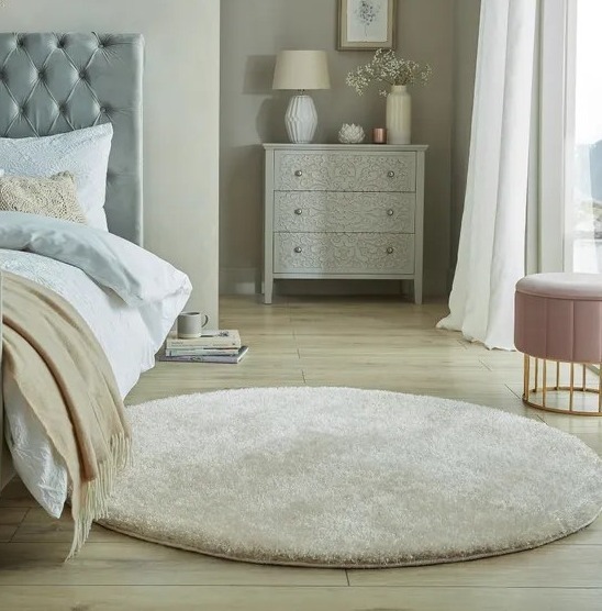 a bedroom with a bed a dresser and a round rug