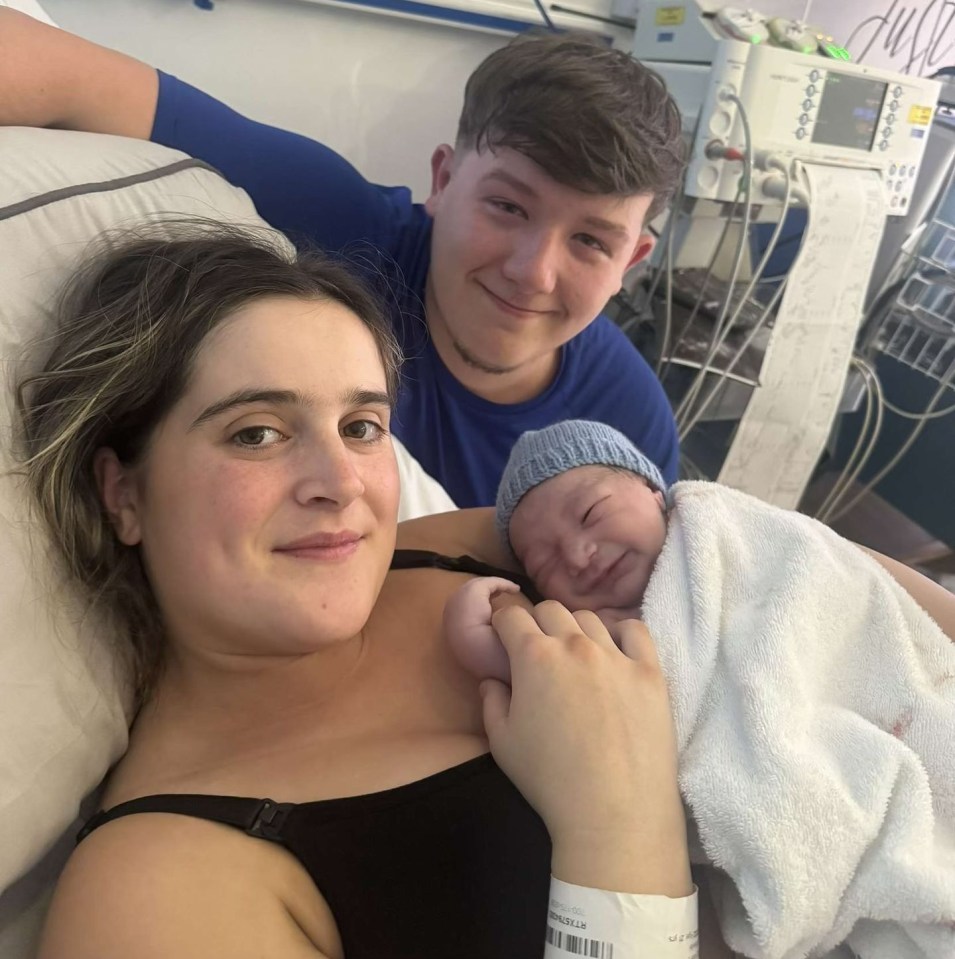 a man and woman hold a newborn baby in front of a sign that says capable and strong