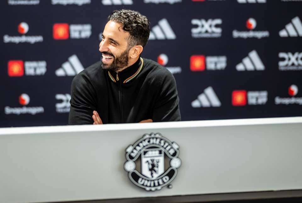 a man sitting in front of a manchester united logo