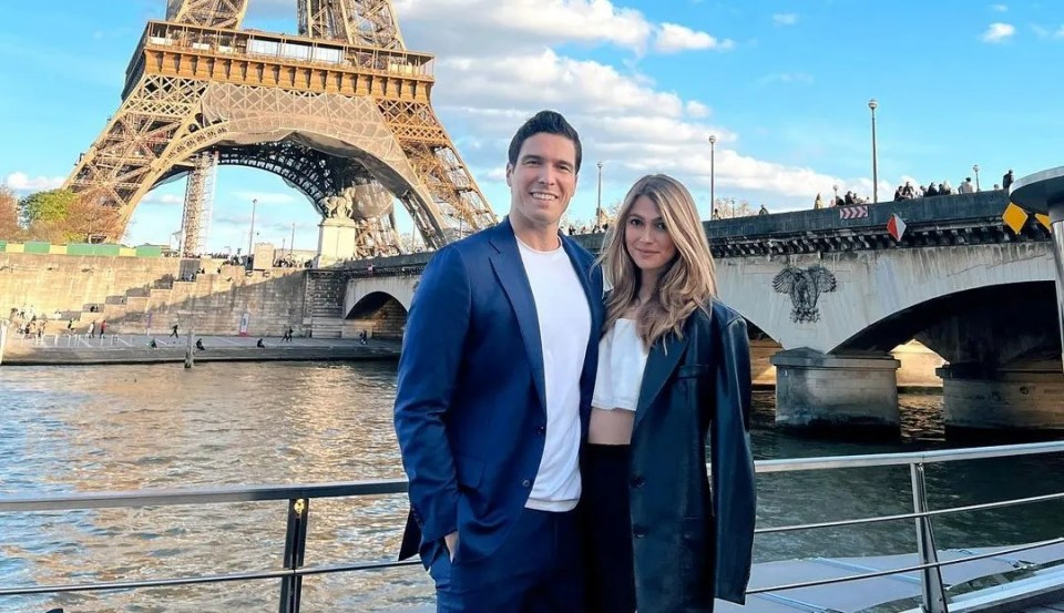 a man and woman pose in front of the eiffel tower