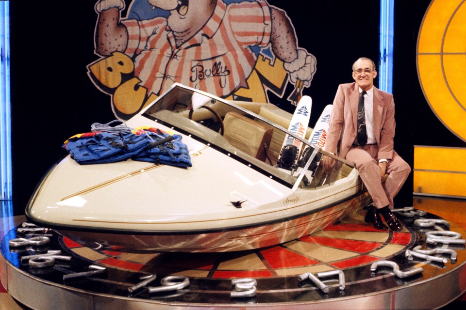 a man sits next to a boat that says bells on it