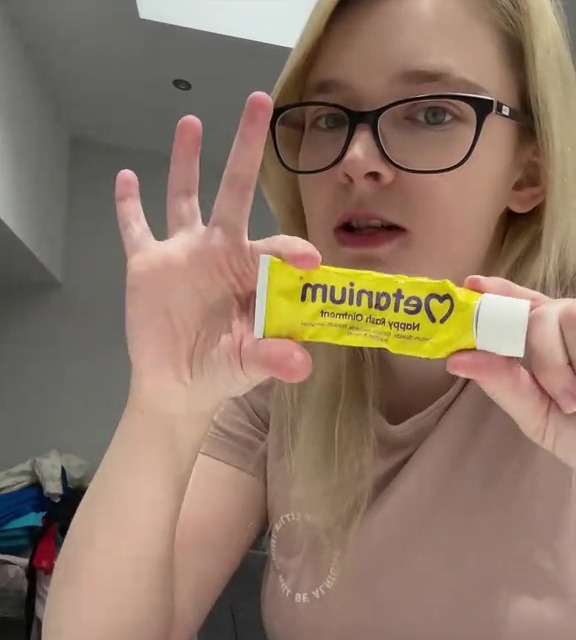 a woman is holding a tube of muinote cream