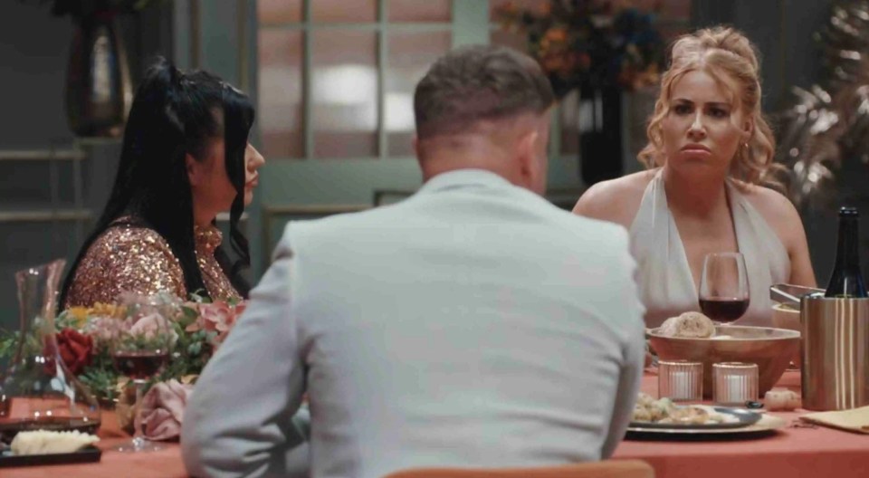 a man in a suit sits at a table with two women