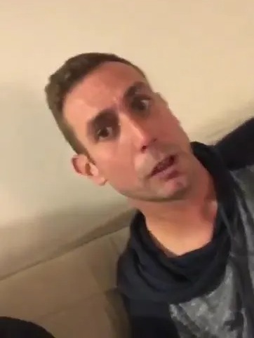 a man is sitting on a couch making a funny face .