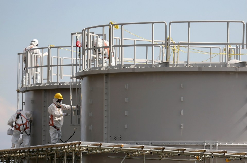 workers paint a tank with the number 1-3-3 on it