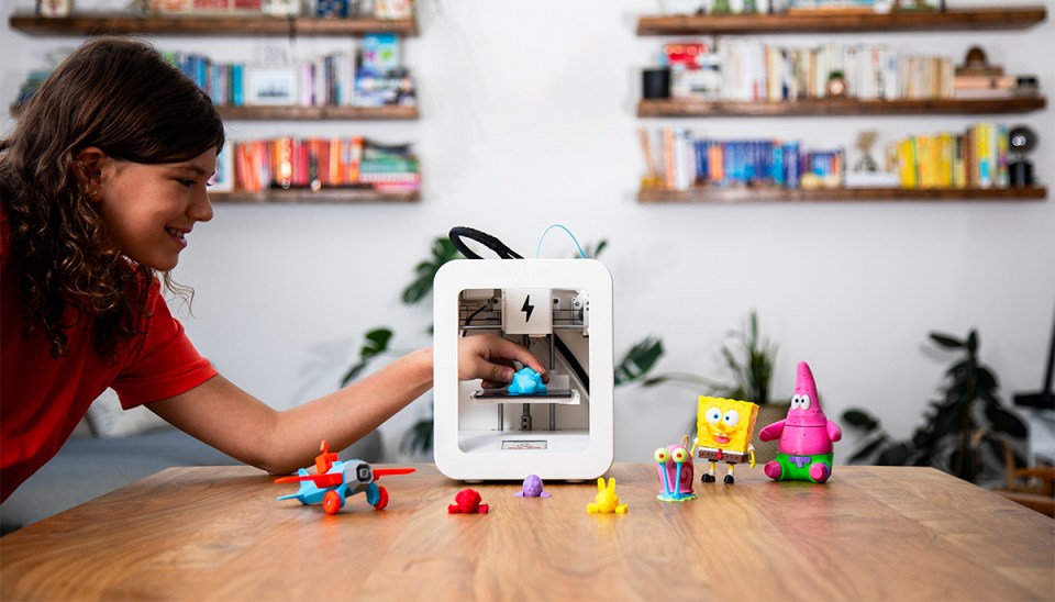 A child using a 3D printer to create small figurines.