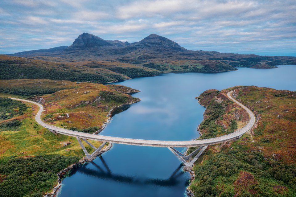 a bridge over a body of water with mountains in the background