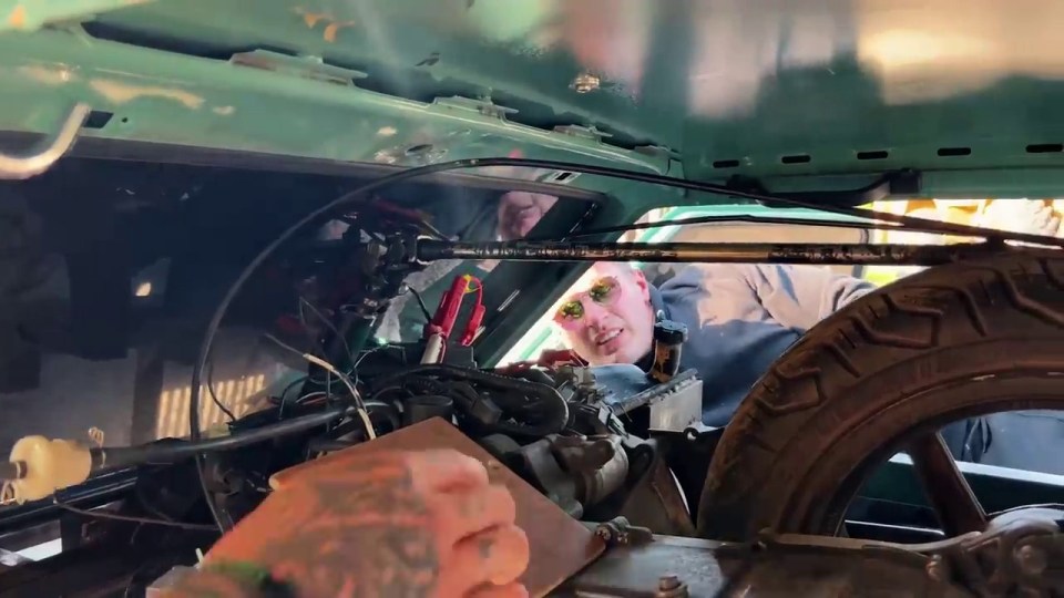 a man wearing sunglasses is working on a car engine
