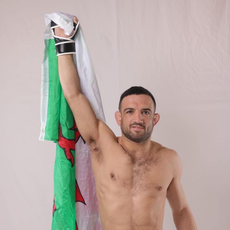 a shirtless man is holding a flag over his head