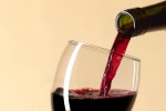 a glass of red wine is being poured from a bottle