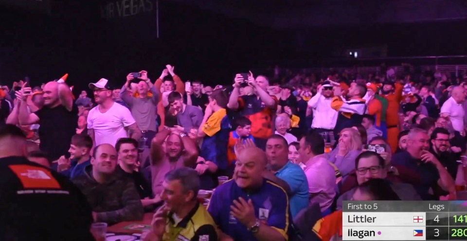a crowd of people watching a game with a scoreboard that says first to 5