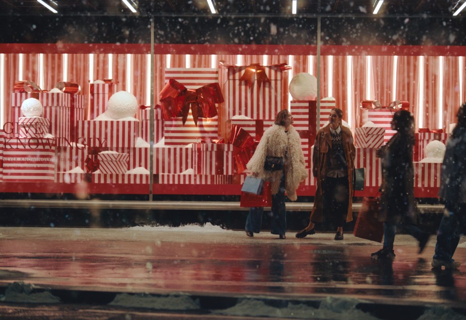 people walking in front of a store window that says christmas