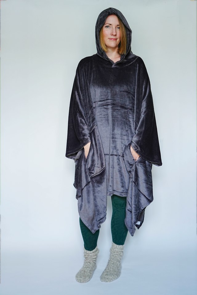 a woman wearing a grey poncho with a hood