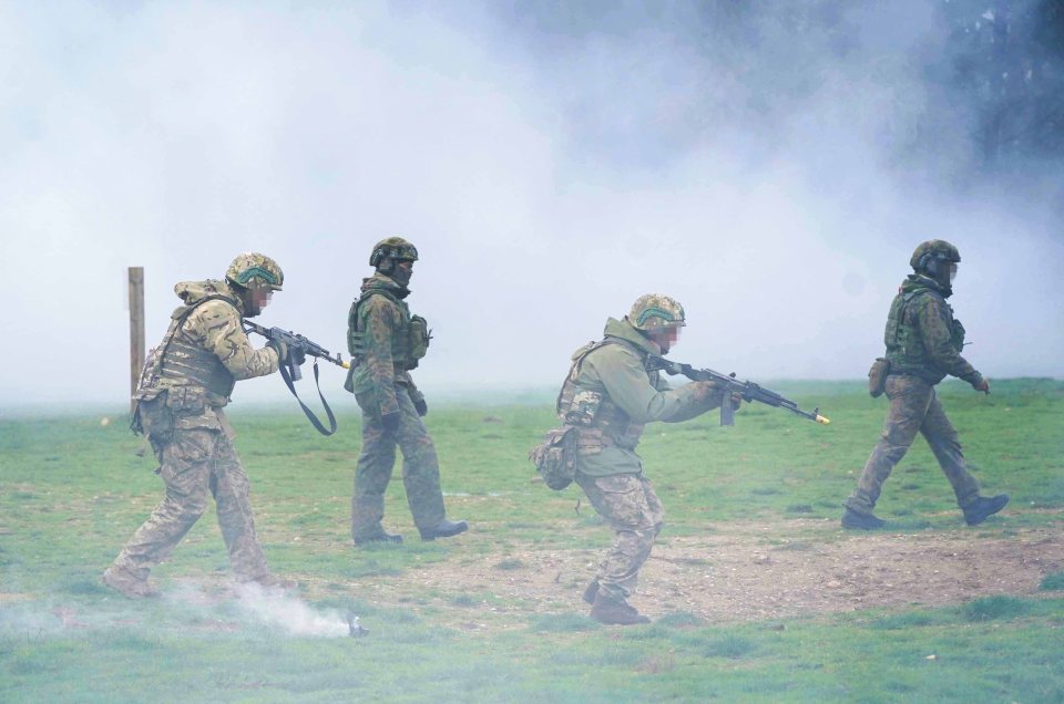 a group of soldiers are walking through a field with smoke coming out of it