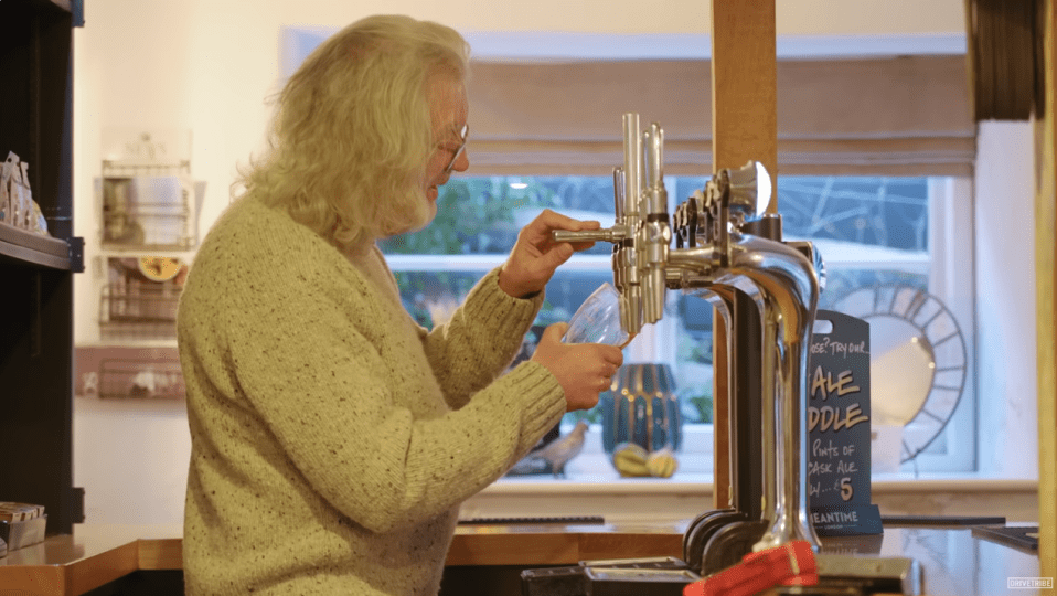 a man pouring a glass of ale from a tap