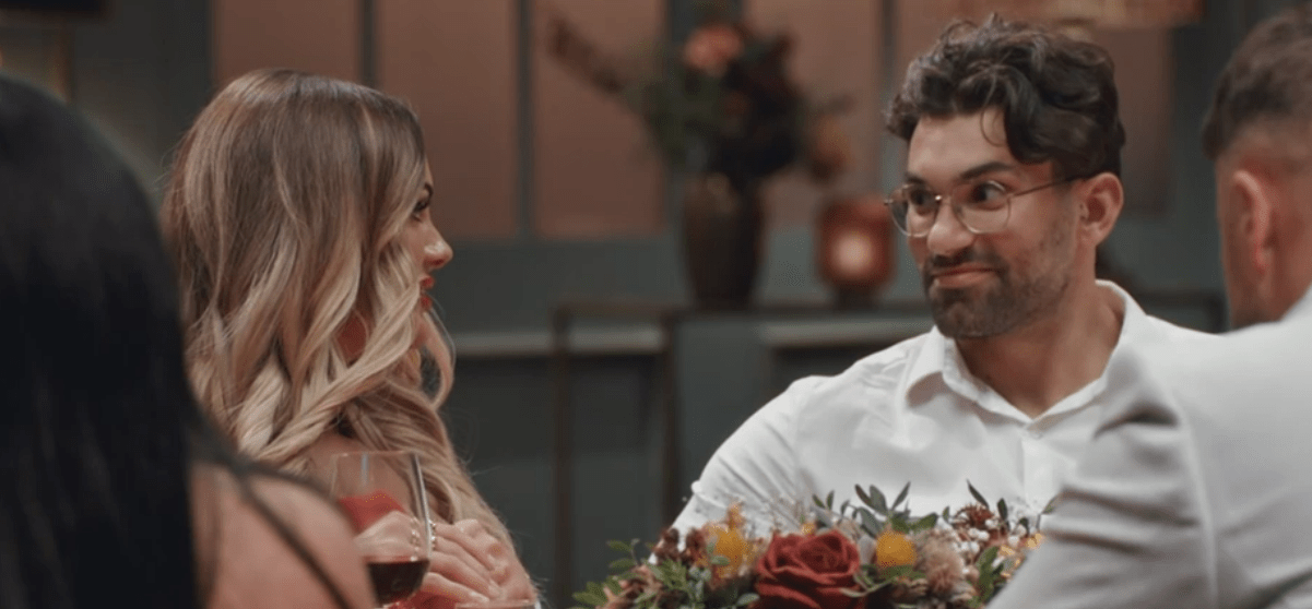 a man with glasses sits at a table with a woman