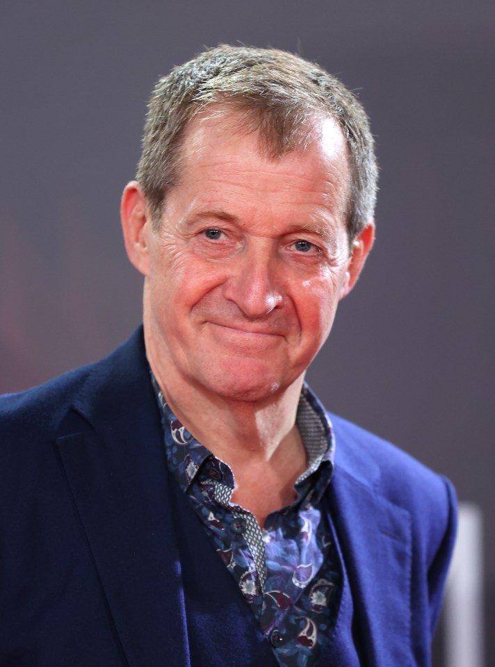 a man in a blue suit and floral shirt smiles for the camera