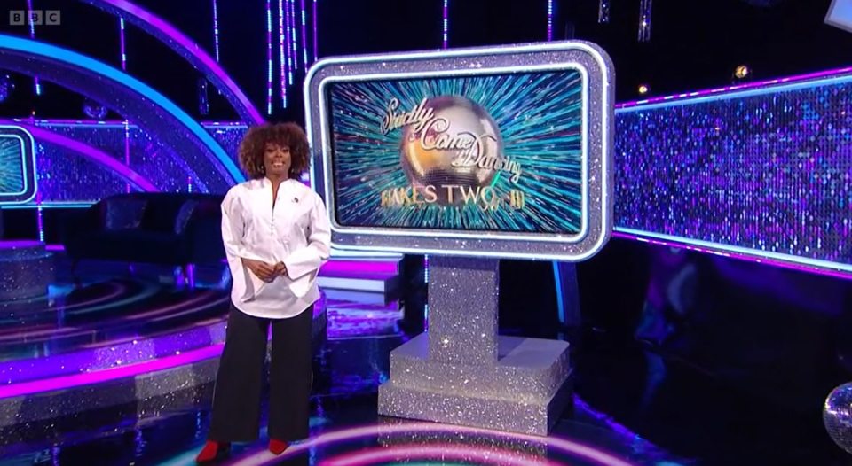 a woman stands in front of a large screen that says strictly come dancing
