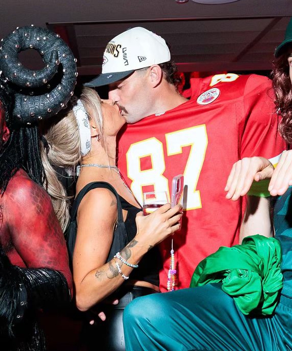a man in a red jersey with the number 87 on it kisses a woman