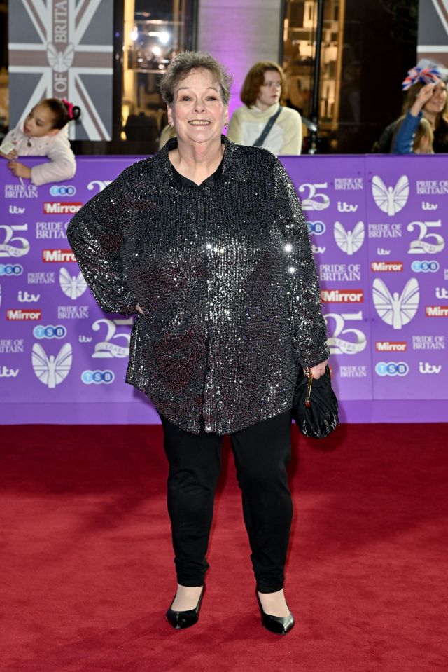 a woman stands on a red carpet that says pride of britain