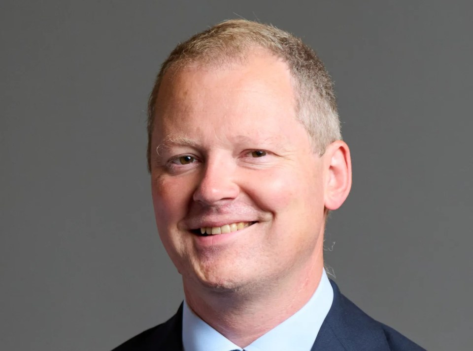 a man in a suit and tie smiles for the camera