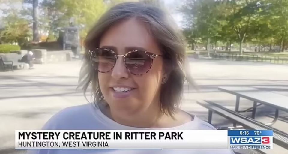 a woman wearing sunglasses is smiling in front of a sign that says mystery creature in ritter park