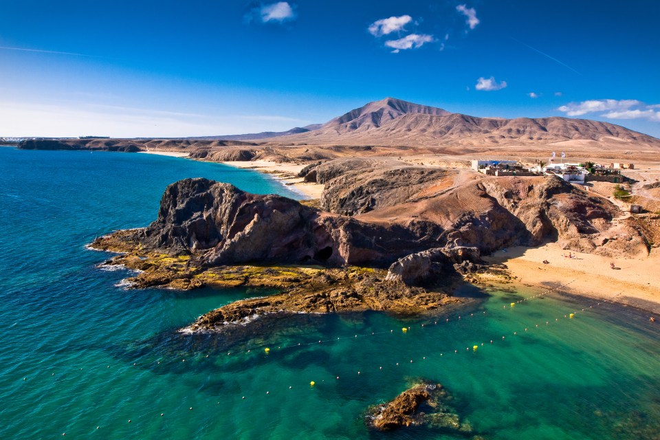 a beach with mountains in the background and waves crashing on the sand