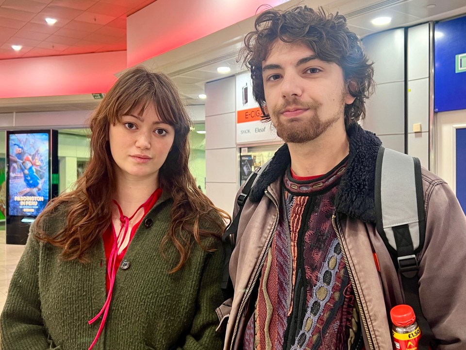 a man and a woman are standing next to each other in front of a sign that says fcg