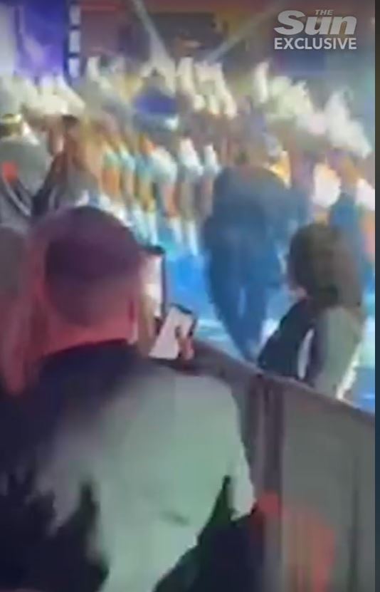 a man is holding a cell phone in front of a crowd of people at a concert .
